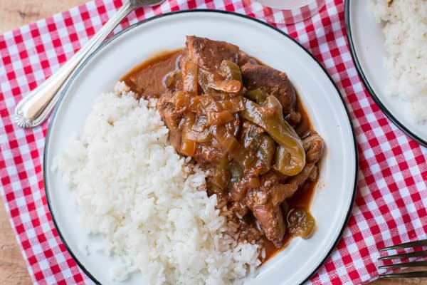 plate with white rice and barbecue country style ribs with red and white napkin under it.