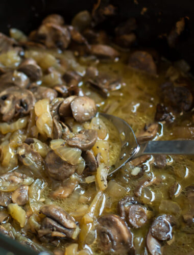 cooked mushrooms and onions in a buttery sauce in slow cooker