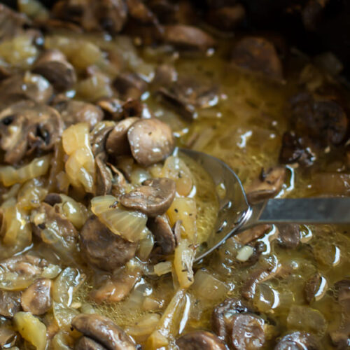 cooked mushrooms and onions in a buttery sauce in slow cooker