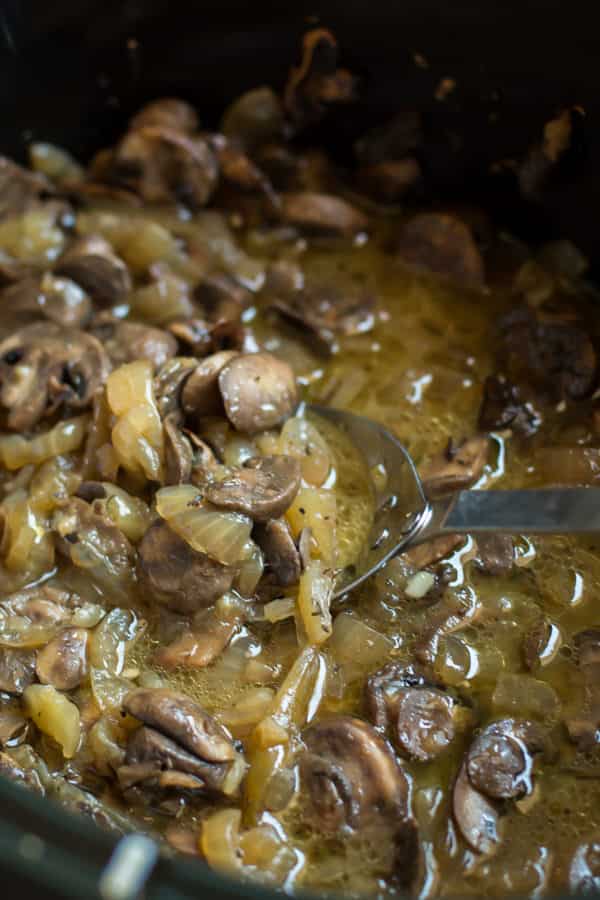 cooked mushrooms and onions in a buttery sauce in slow cooker