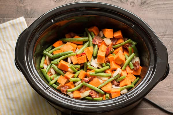 Vegetables and bacon in slow cooker not cooked yet.