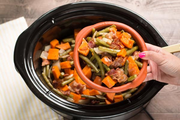 Sweet Potatoes, Green Beans and Bacon in slow cooker and bowl of it in front.