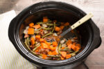 sweet potatoes and green beans with spoon in it in slow cooker