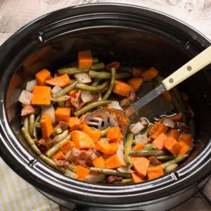 sweet potatoes and green beans with spoon in it in slow cooker