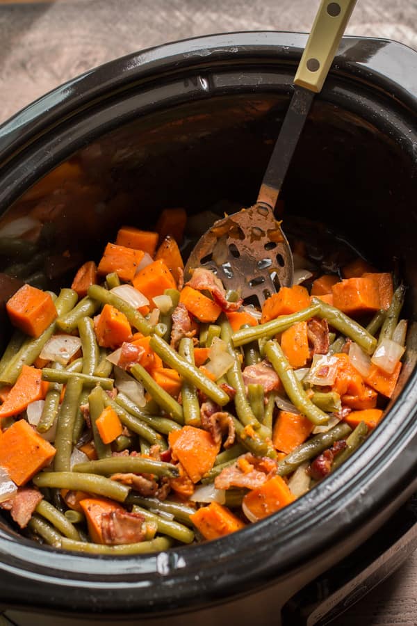 sweet potatoes and green beans in slow cooker with spoon in it.