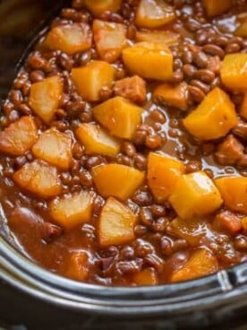 baked beans with chunks of pineapple on top in slow cooker.