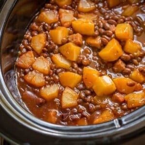 baked beans with chunks of pineapple on top in slow cooker.