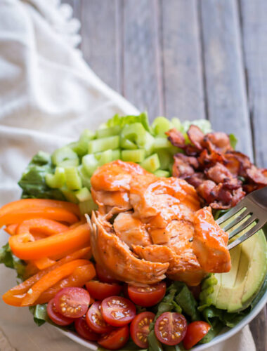 close up of honey buffalo turkey breast, sliced on top of a salad