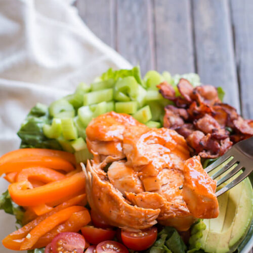 close up of honey buffalo turkey breast, sliced on top of a salad