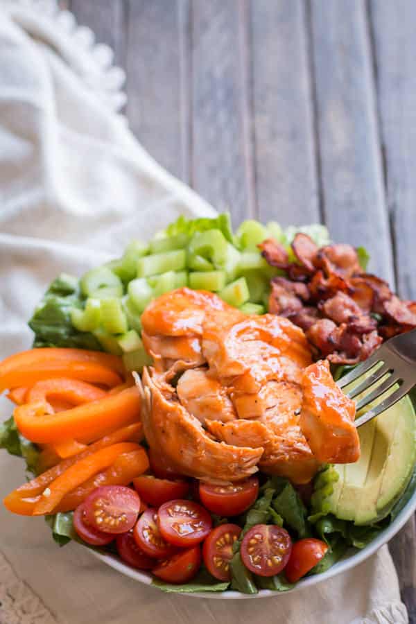 sliced honey buffalo turkey breast on top of a salad.