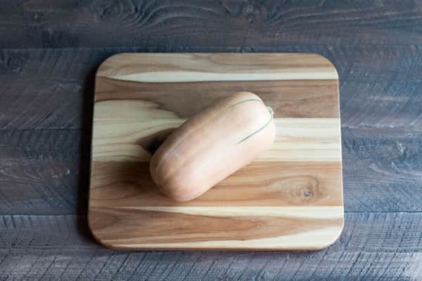 One whole butternut squash on a cutting board.