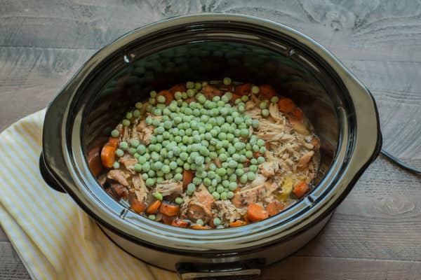 peas on top of shredded chicken in a slow cooker