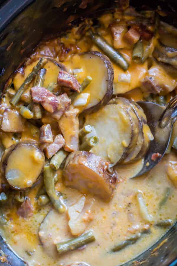 sliced potatoes, ham and green beans in a slow cooker.