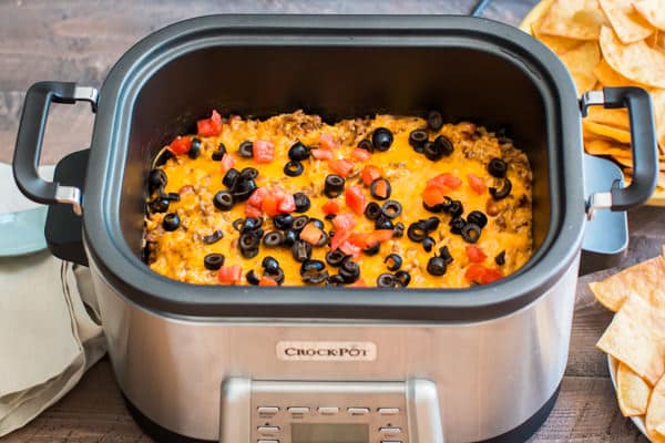 beefy enchilada dip in a slow cooker with tomatoes and olives