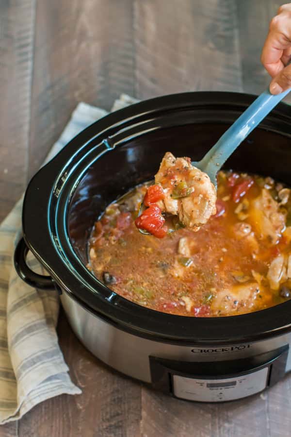chicken cacciatore in a slow cooker with tomatoes and bell peppers.