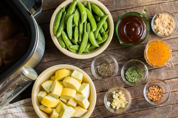 snow peas, squash, seasonings, and garlic on a wooden table.