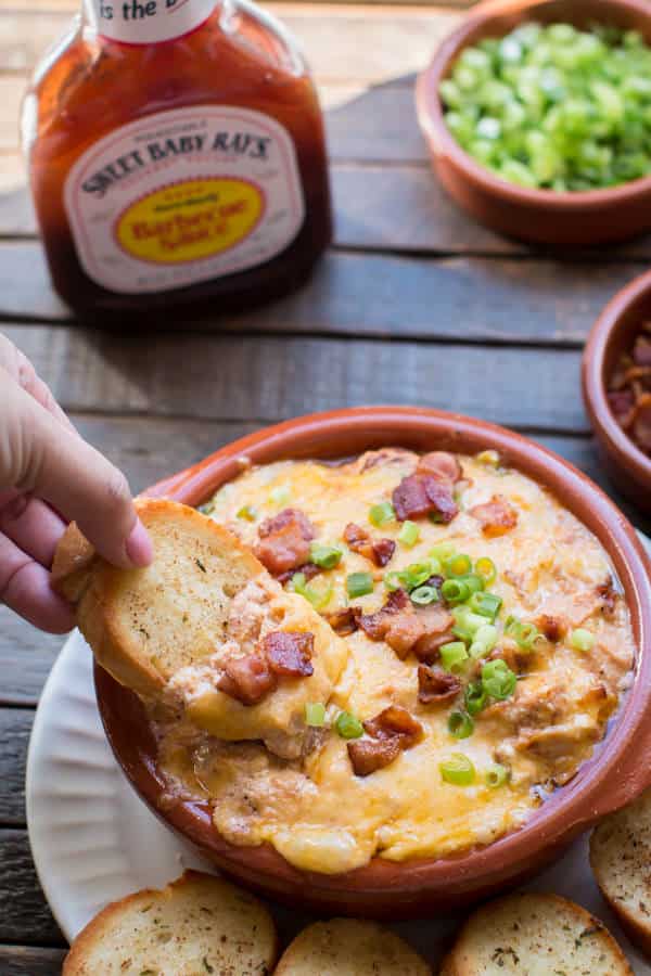 bread scooping barbecue chicken dip from a bowl.