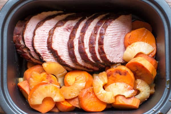 close up of ham and sweet potatoes in a slow cooker.