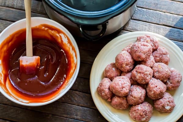 raw meatballs one a plate. Barbecue sauce mixture in a bowl.