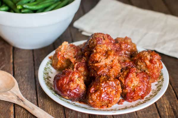 porcupine meatballs on a plate served with a bowl of green beans