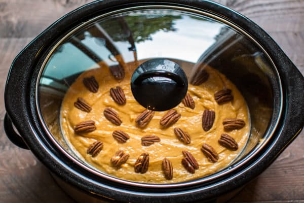 lid on slow cooker with pumpkin cake batter in it.