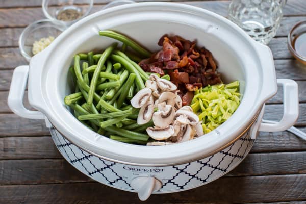 green beans in a slowc cooker with mushrooms, cooked bacon and leeks.