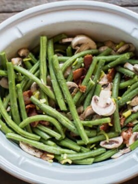 green beans mushrooms and bacon stirred together in a slow cooker.