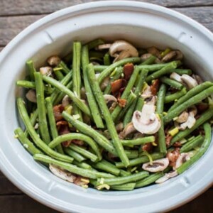 green beans mushrooms and bacon stirred together in a slow cooker.