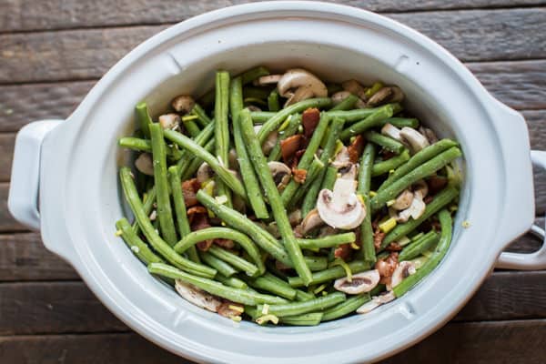 green beans mushrooms and bacon stirred together in a slow cooker.