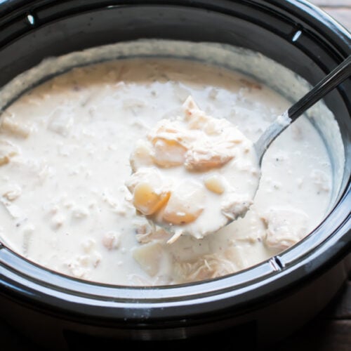 scoop of potato chicken soup coming from a slow cooker.