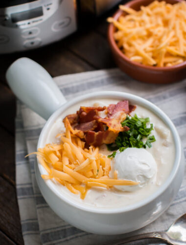 bowl of chicken potato soup with cheese, sour cream, bacon and onion.