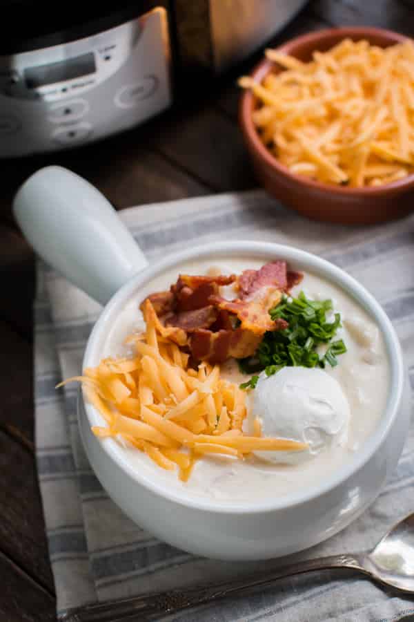 bowl of chicken potato soup with cheese, sour cream, bacon and onion.