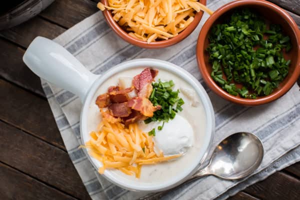 chicken baked potato soup loaded with cheese, sour cream, and green onion in a bowl