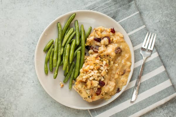 chicken breast with stuffing on plate. Green beans on the side.