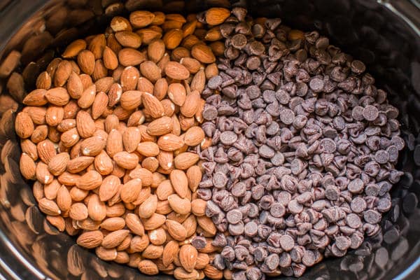 slow cooker with almonds on one side and chocolate chips on other side.