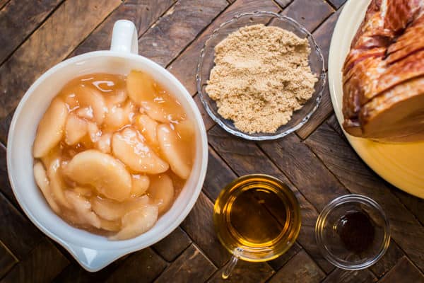 bowl of apple pie filling. Dishes of brown sugar, apple juice and cloves. Spiral ham on a plate.