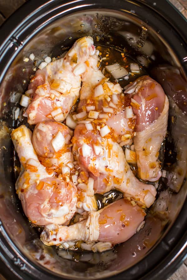 chicken drumsticks raw in a slow cooker with orange marmalade.