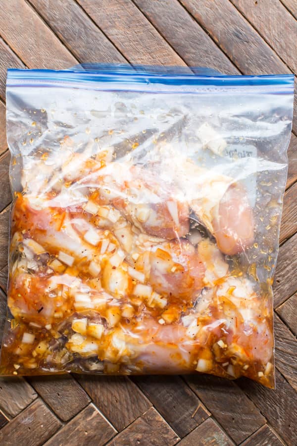 plastic gallon bag with drum sticks, orange marmalade and onion in it.