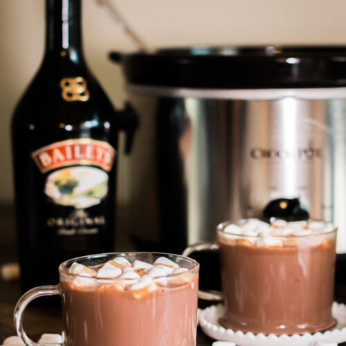 2 cups of baileys hot chocolate with bottle of baileys behind it.