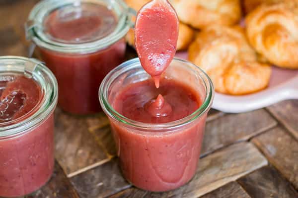 spooning out cranberry apple butter with croissants in the background.