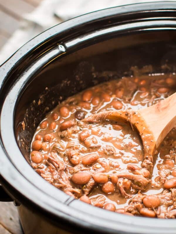 all done cooking pinto beans and beef with a wooden ladle in it.