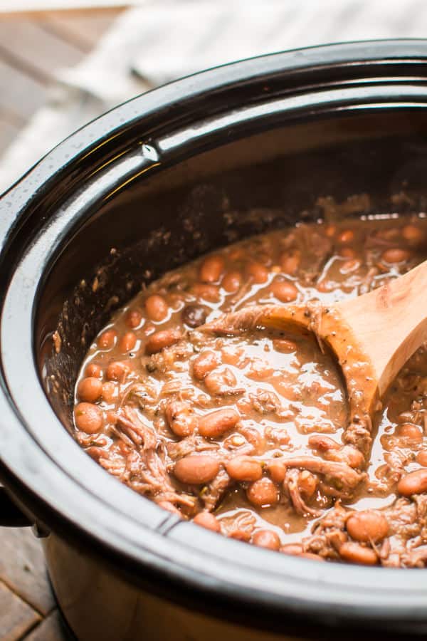 all done cooking pinto beans and beef with a wooden ladle in it.