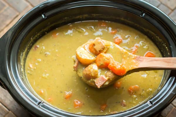 scoop of split pea stew coming from a slow cooker.