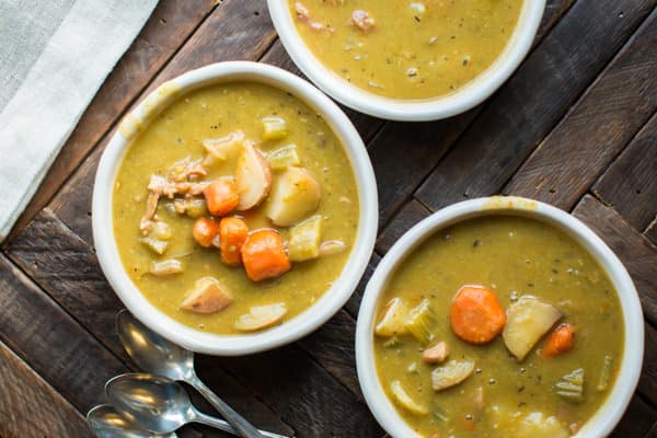 3 bowls of split pea stew on a wooden table.