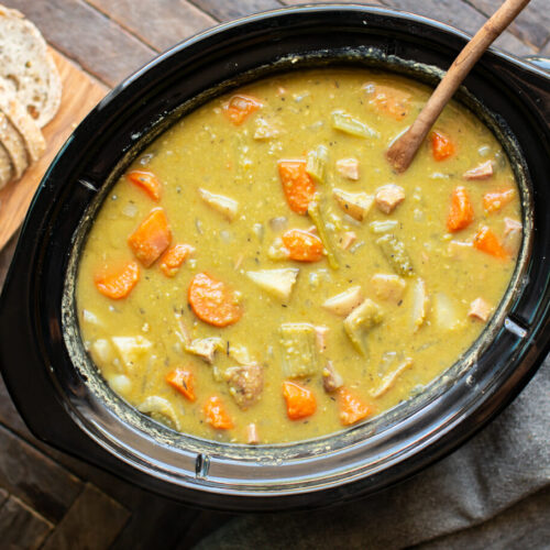 split pea stew in a slow cooker with wooden ladle in it.