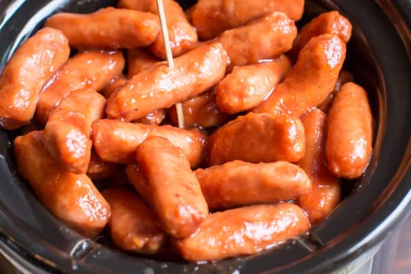 selecting an apple butter little smokies sausage with a toothpick.