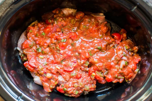 homemade salsa over chicken thighs in a slow cooker.