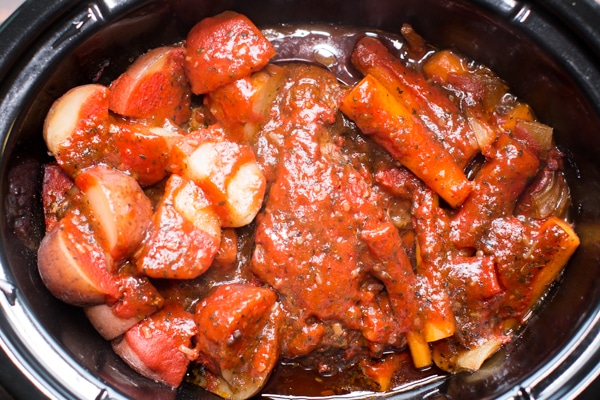 cooked italian pot roast with carrots and celery in a slow cooker.