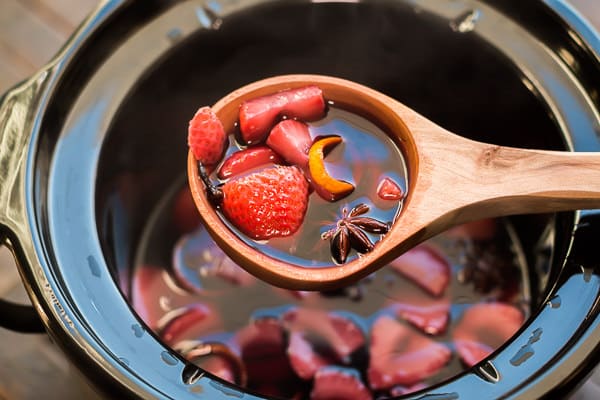 scoop of mulled wine with crockpot in background
