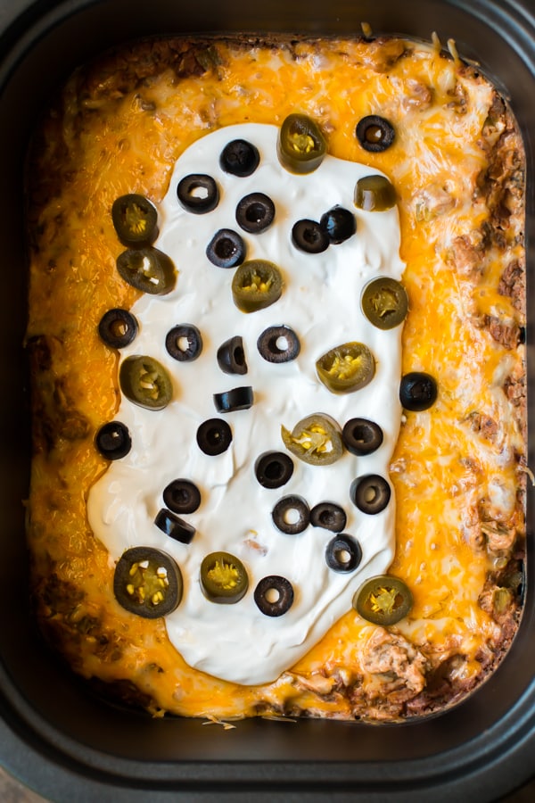 Bean dip with cheese, sour cream and olives on top.